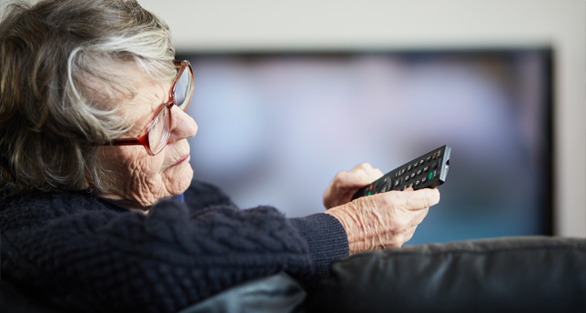 Femme âgée tenant la télécommande de la télévision